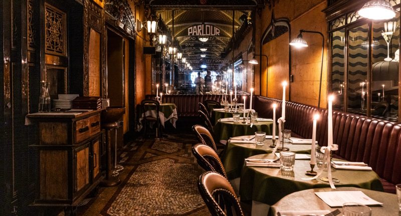 Elegant dining area at The Parlour in QT Sydney with candlelit tables and vintage decor, perfect for a luxury dog-friendly stay in NSW with pet-friendly dining options.