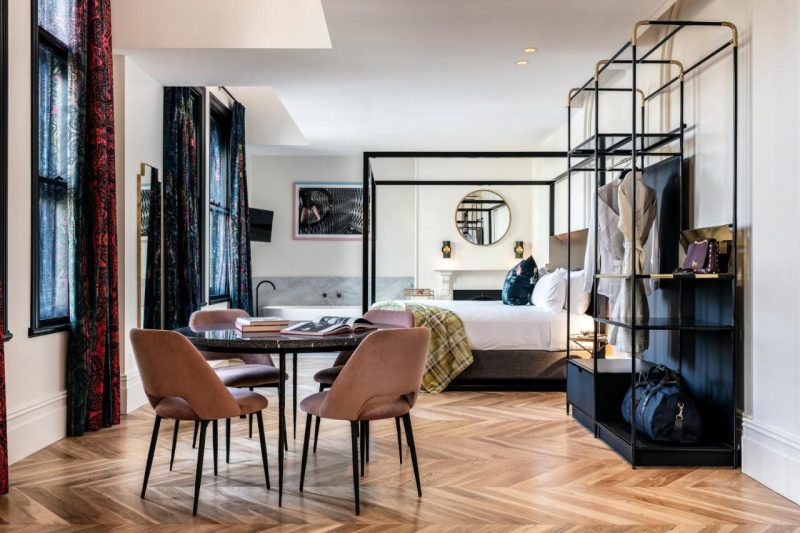 Elegant hotel room at Crystalbrook Albion with hardwood floors, high ceilings, a four-poster king bed, and a perfect mix of old-world charm and modern luxury.